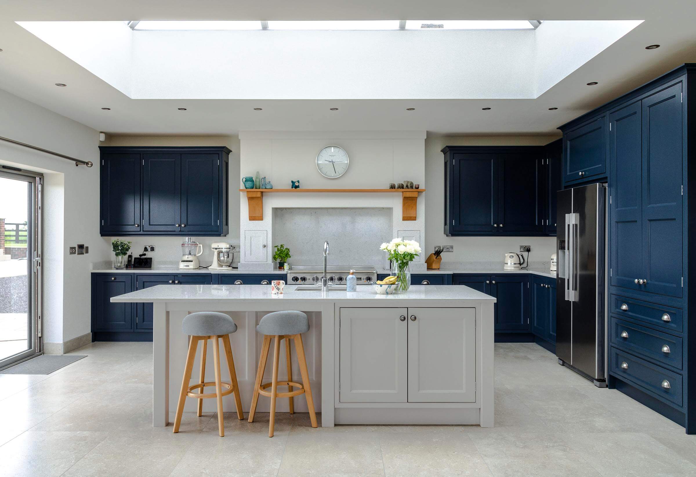 A stylish classic contemporary kitchen in blue and white handmade from solid wood, light spills into the room from a large skylight