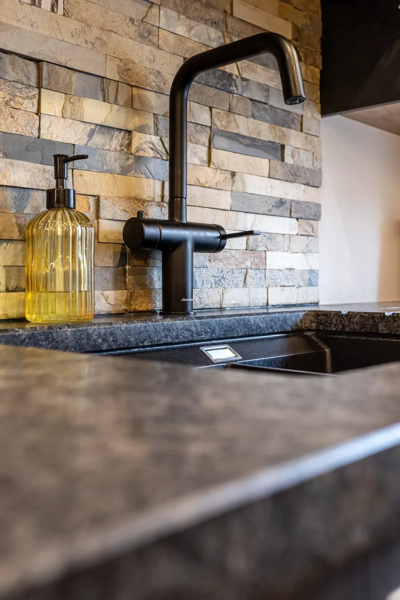 View of a kitchen built by Scawton Kitchens featuring a granite worktop and black kettle tap by Clearwater